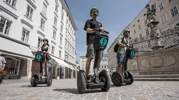 Drei Personen fahren auf Segways in einer Stadt.