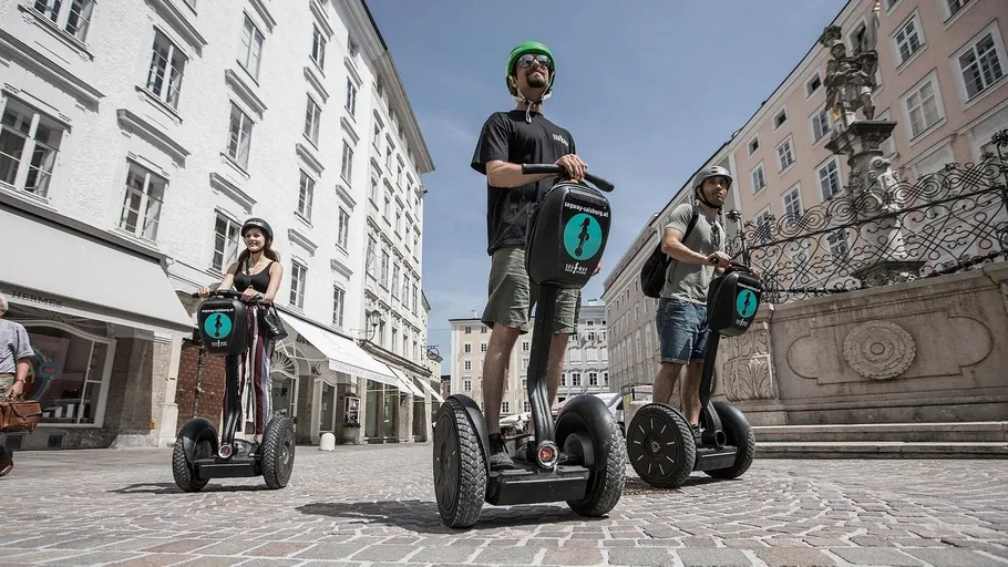 Drei Personen fahren auf Segways in einer Stadt.
