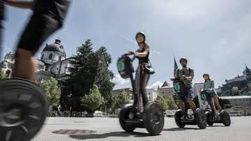 Personen fahren Segways auf einem Stadtplatz.