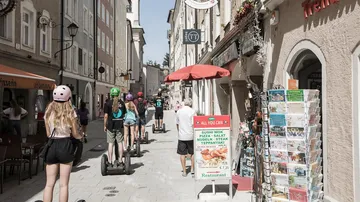 Menschen fahren Segways auf einer engen Straße.