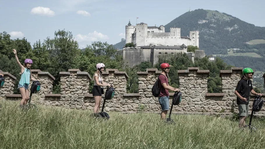 Personen fahren Segways nahe einer historischen Burg.