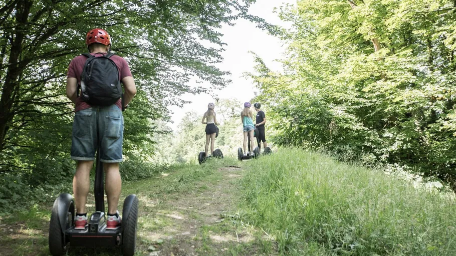 Menschen fahren Segways auf einem Waldweg.
