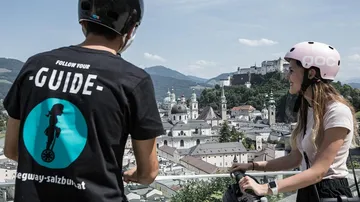 Zwei Personen auf Segways mit Blick auf Salzburg.