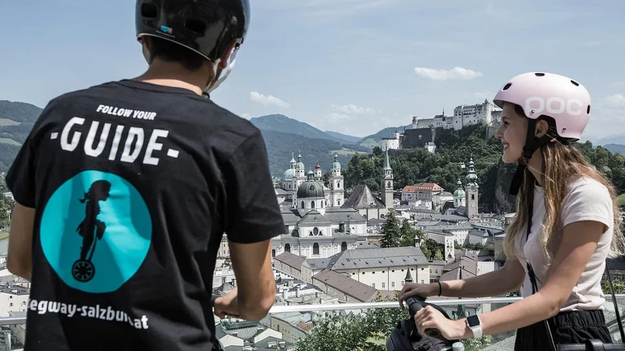 Zwei Personen auf Segways mit Blick auf Salzburg.