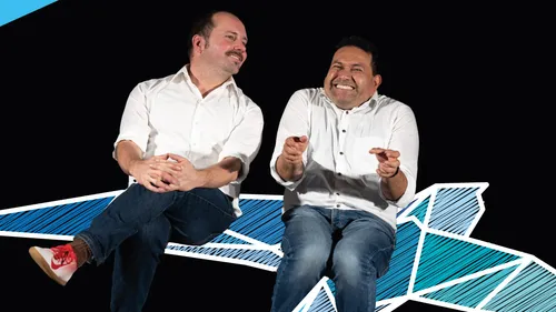 Two men laughing, sitting on paper airplane.