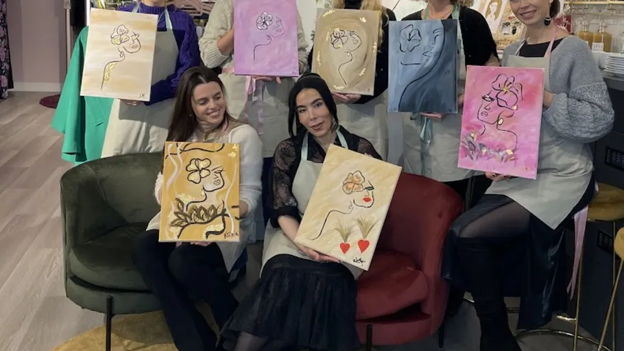 Group holding abstract flower paintings indoors.