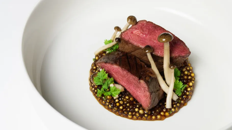 Plated beef slices with mushrooms and sauce.