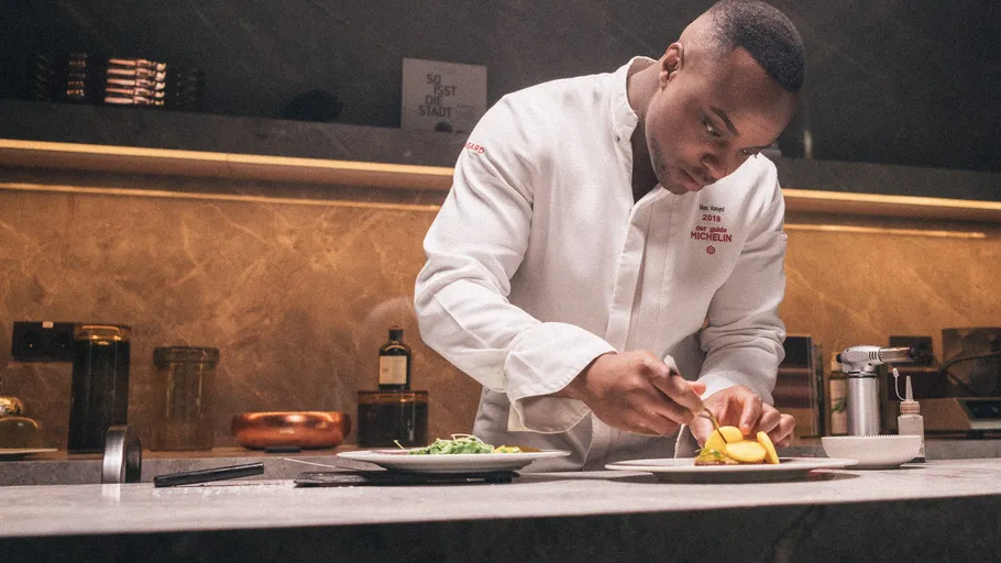Chef plating food in a modern kitchen.