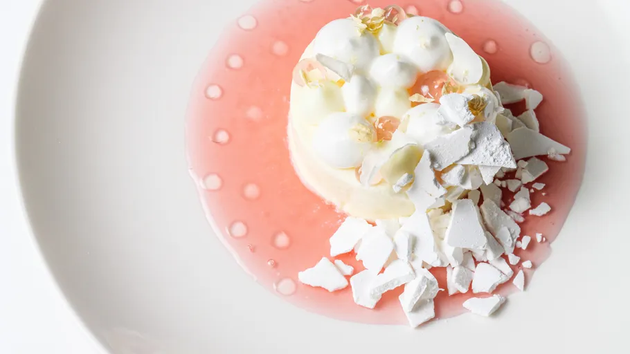 Dessert mit Baiser in rosa Soße auf Teller.