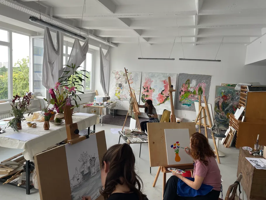 Artists painting in a bright studio.