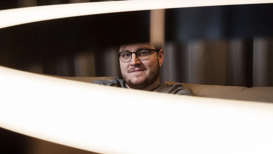 Mann mit Brille hinter gebogenem Leuchtkörper.