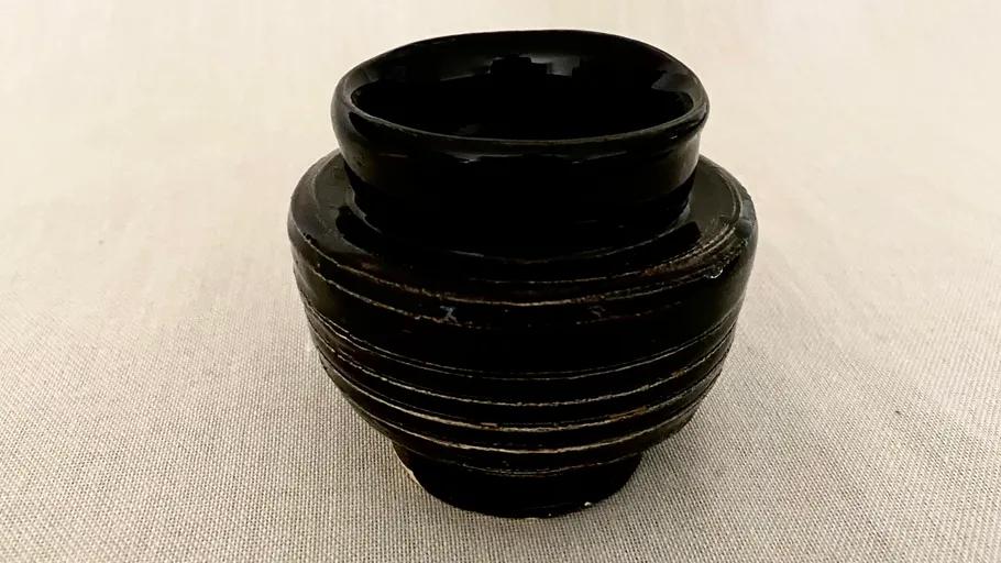 Schwarze Keramiktasse auf beigem Hintergrund.