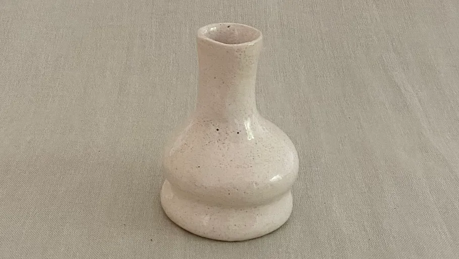 Keramikvase auf beigefarbenem Stoff.