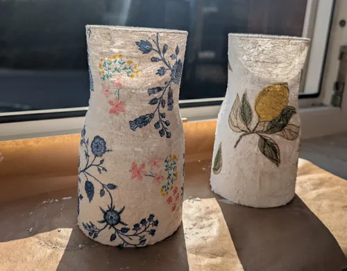 Two decorative vases with floral designs on windowsill.