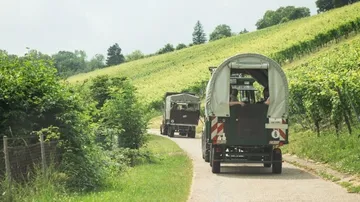 Tractors driving through vineyard on a sunny day.