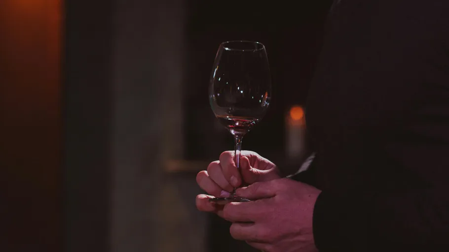 Person holding wine glass in dim setting.