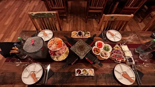 Abendessenstisch für Raclette mit Tellern und Besteck gedeckt.