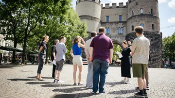 Tour group listening near historical gate.