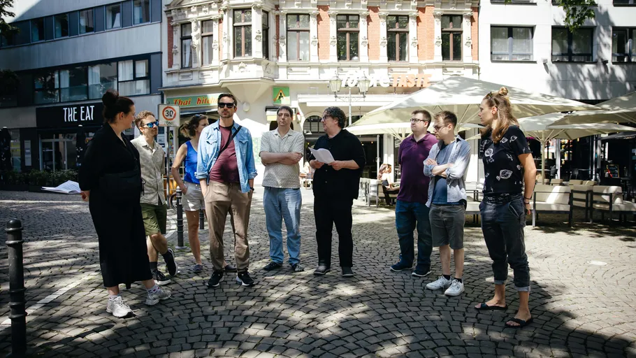 Group of people standing on cobblestone street.