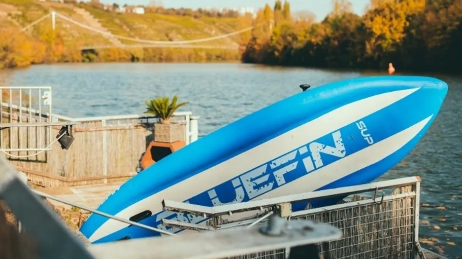 Blaues Kajak auf Steg am Fluss.