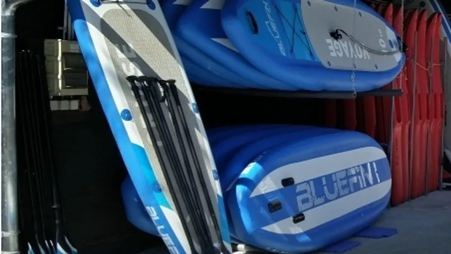 Stacked blue paddleboards in storage area.
