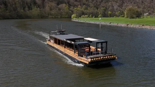 Breites Holzboot schwimmt auf einem Fluss.