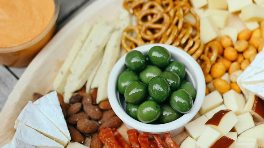 Cheese platter with olives, pretzels, and nuts.