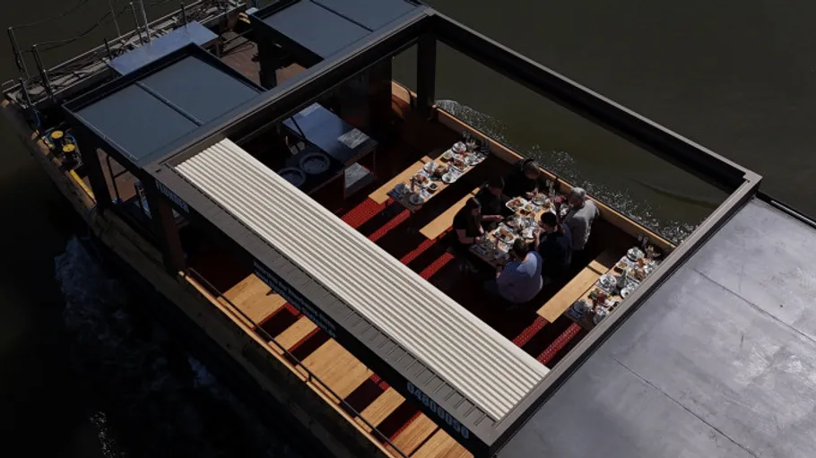 Menschen essen auf einem Boot mit überdachten Sitzplätzen.