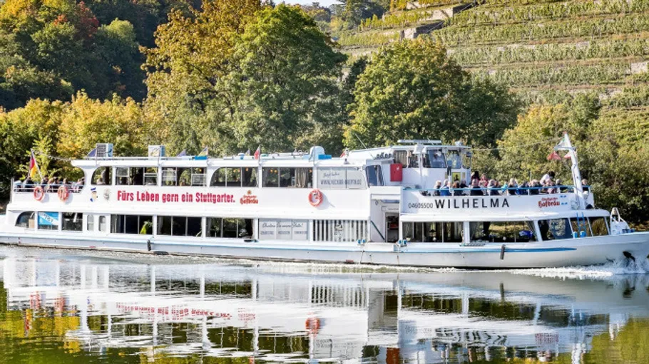 River boat cruising by forested hillside.