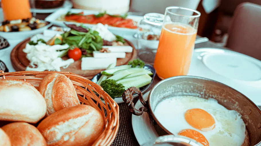 Frühstückstisch mit Eiern, Brot und Saft.
