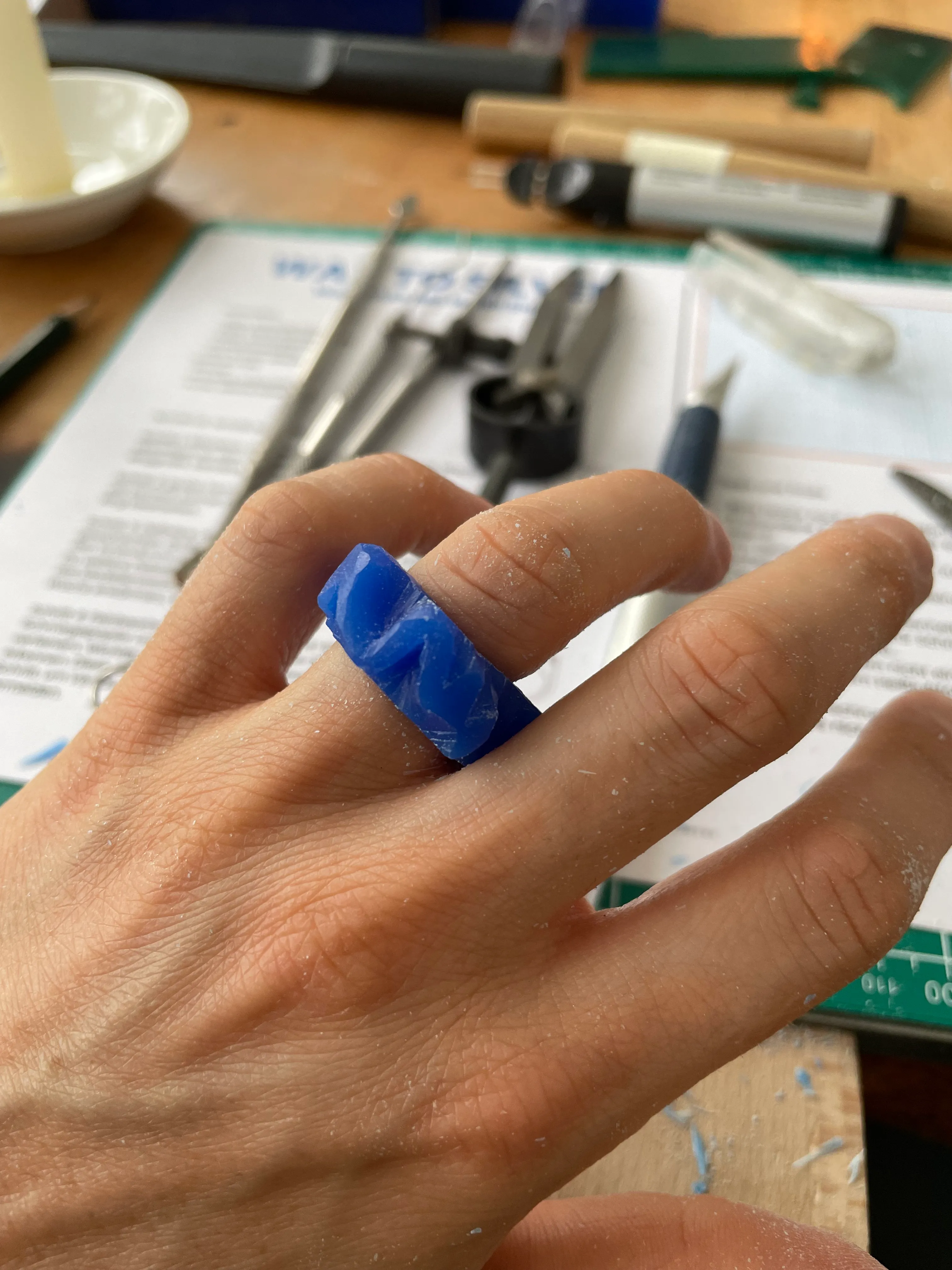 Hand trägt blauen Wachsring am Arbeitstisch.