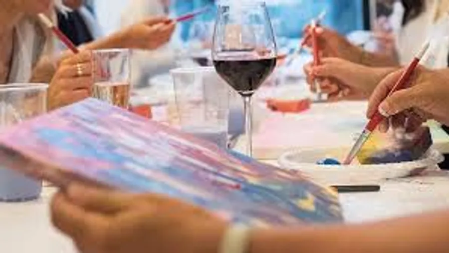 People painting with wine glasses nearby.