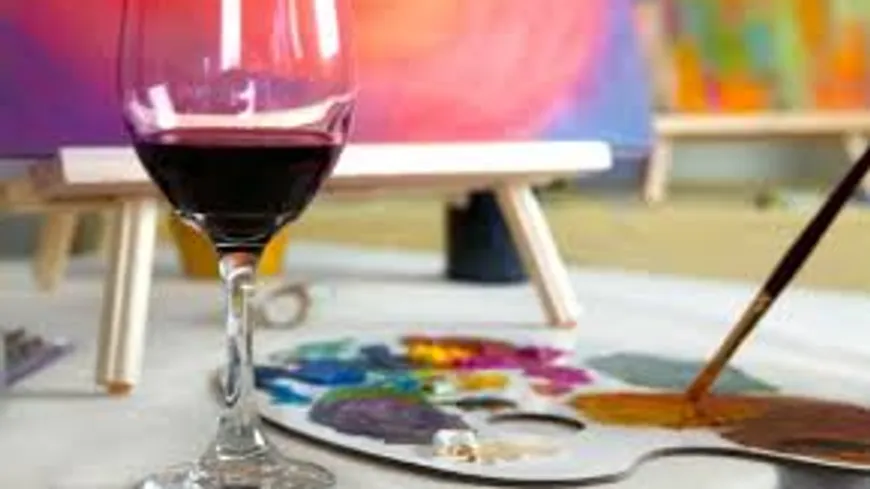 Wine glass, paint palette on white table.