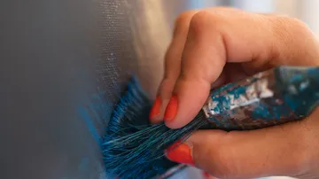 Hand painting blue on canvas with brush.