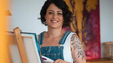 Frau lächelt beim Malen im Kunststudio.