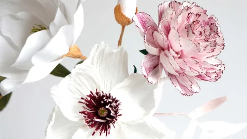 Papierblumen vor neutralem Hintergrund arrangiert.