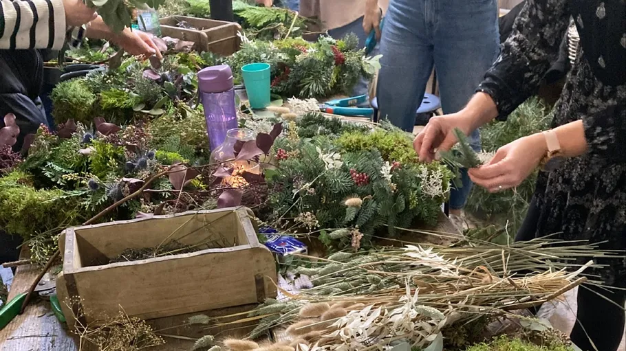 People crafting wreaths at a workshop table.