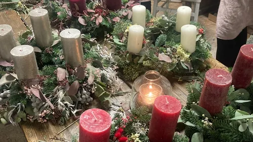 Decorative wreaths with candles on wooden table.