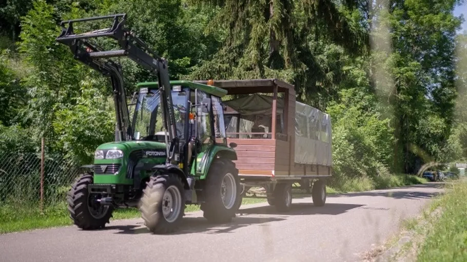 Traktor zieht überdachten Anhänger auf einer Straße.