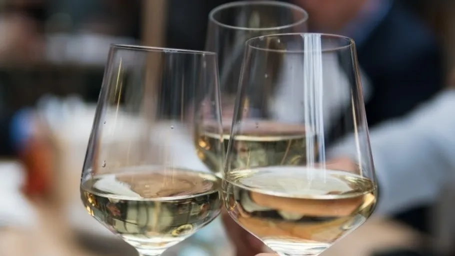 Three wine glasses clinking in a celebratory setting.