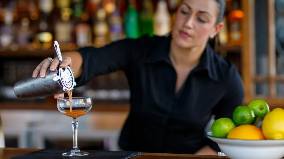 Barkeeperin gießt Cocktail an der Bar ein.