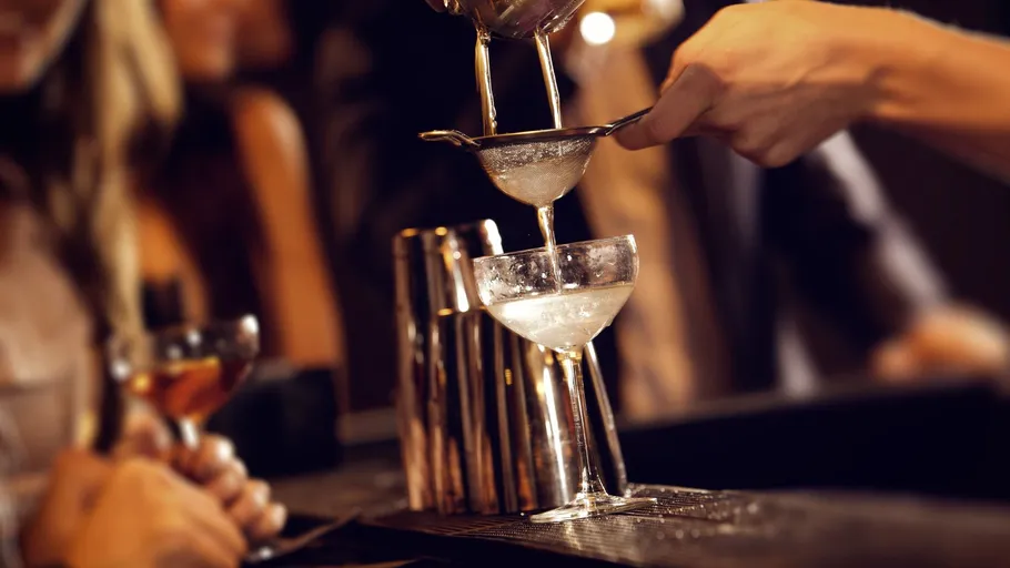 Barkeeper gießt Cocktail durch Sieb.