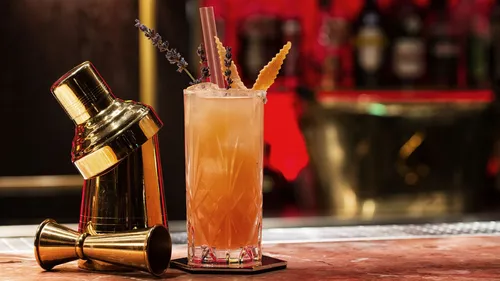 Cocktail beside shaker on bar counter.