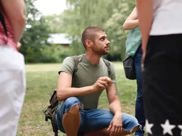 Mann sitzt und spricht mit Gruppe im Freien.