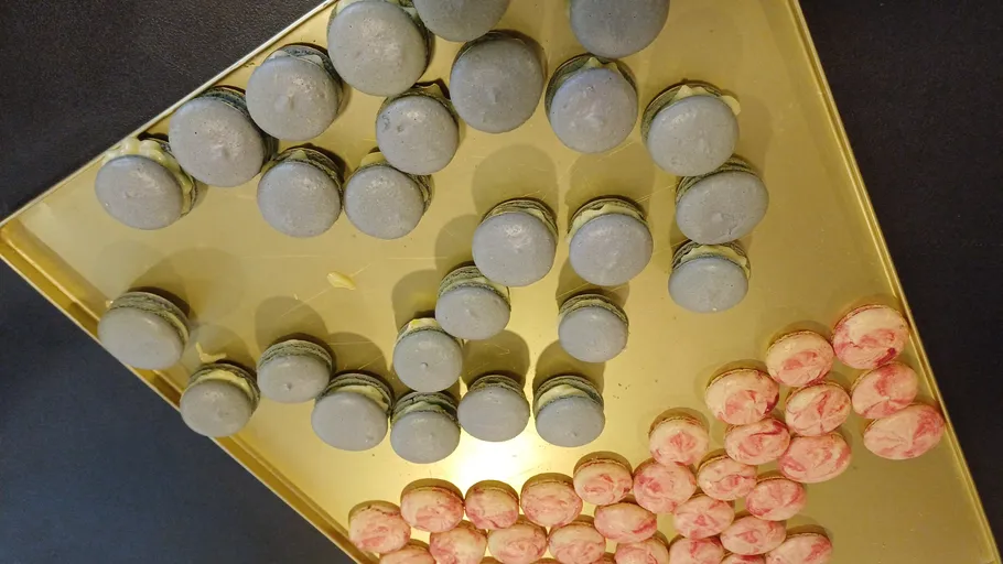 Blue and pink macarons on a gold tray.