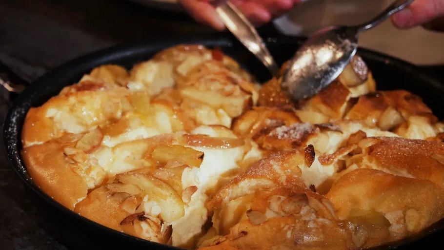 Hände servieren Apfel-Dessert aus Backform.