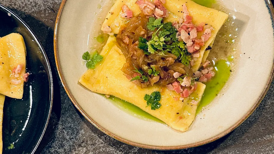 Ravioli with bacon, onions, and herbs on plate.