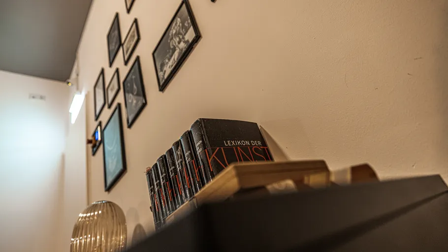 Kunstbücher im Regal mit gerahmten Fotos.