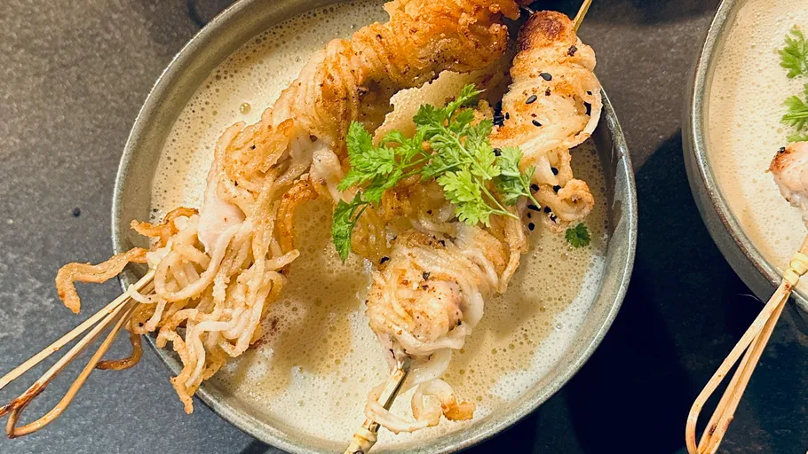 Gespießter Meeresfrüchte auf cremiger Suppe im Schüssel.