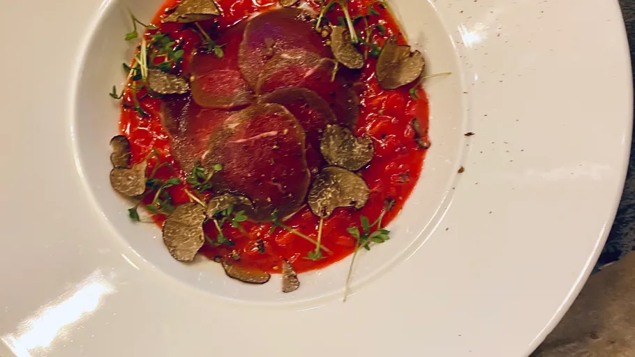 Plated beef carpaccio with truffle shavings.